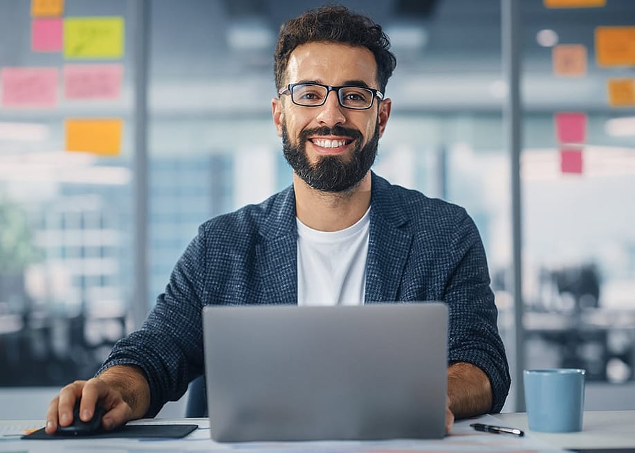 Worker in a modern office smiling while using a laptop. — Gorodenkoff // Shutterstock