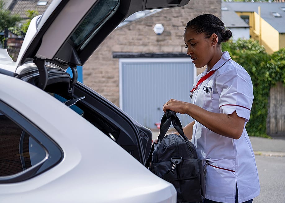 A travel nurse putting her bag in the trunk of her car. — Cultura Creative // Shutterstock