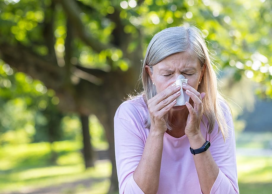 Senior woman outdoors wiping her nose with a napkin. — voronaman // Shutterstock