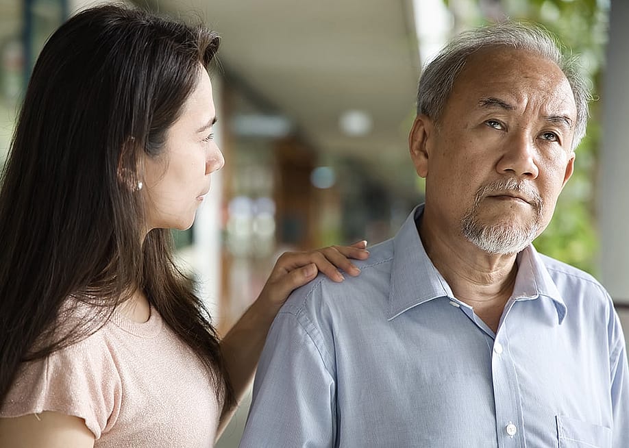 A middle-aged daughter looking worried at his elderly father who has dementia. — 9nong // Shutterstock