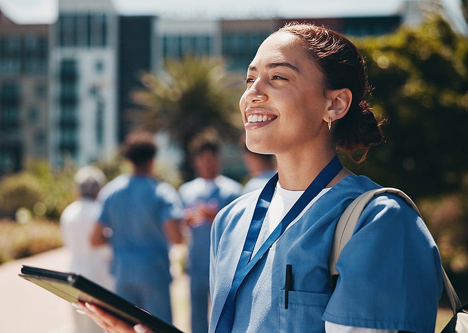 A nursing student happily using a tablet inside campus. — PeopleImages.com - Yuri A // Shutterstock