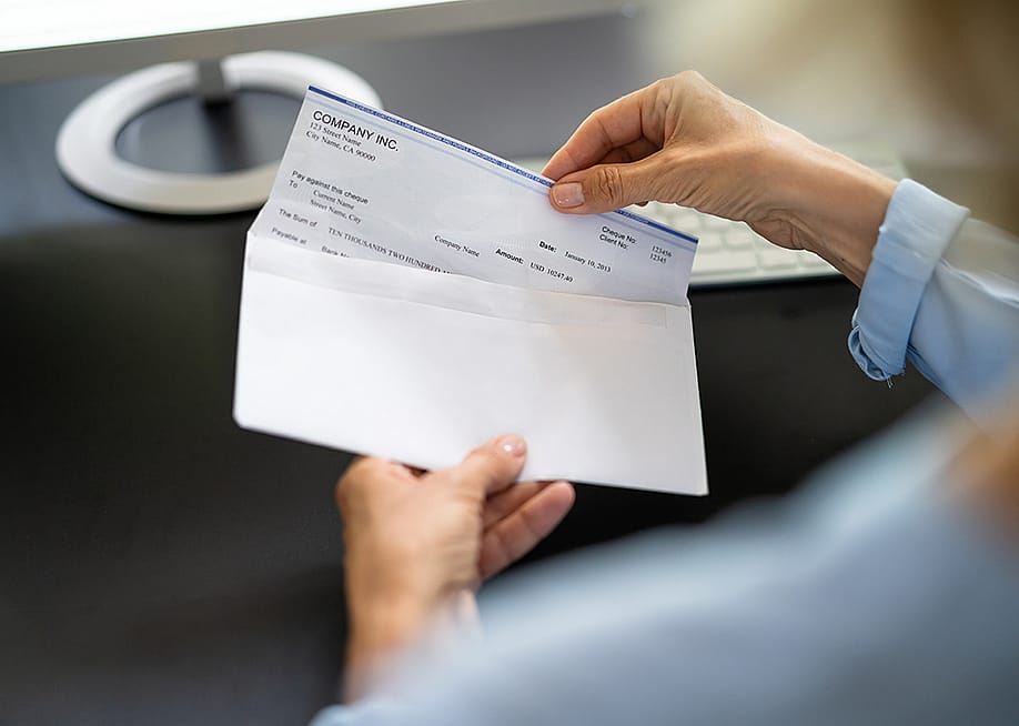 Worker pulling out a paycheck from its envelope. — Andrey_Popov // Shutterstock