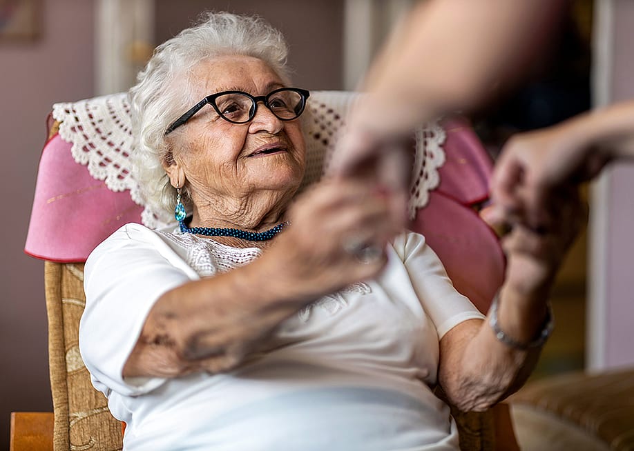 An elderly woman being assisted by her caregiver to stand up. — pikselstock // Shutterstock