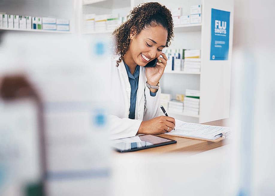 A pharmacist taking a call and listing a customer's order. — PeopleImages.com - Yuri A // Shutterstock
