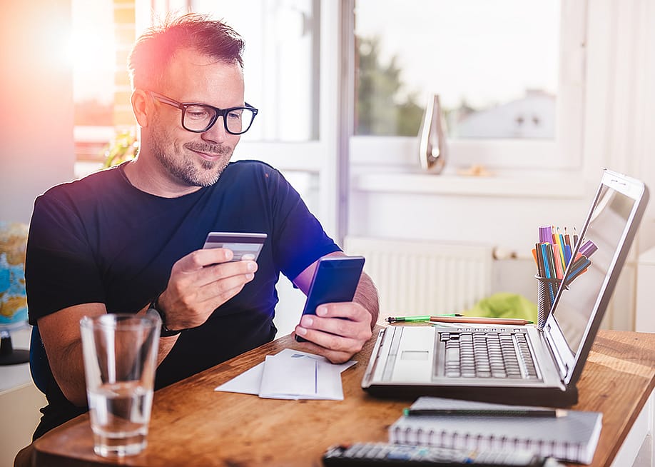 Man in his home office using a credit card for an online transaction. — Zivica Kerkez // Shutterstock