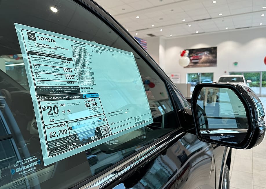 A car dealer's pricing sticker on a Toyota Tundra vehicle. — Kenishirotie // Shutterstock