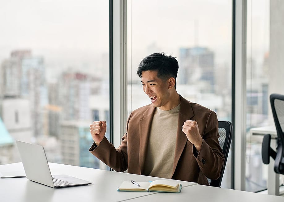 Businessman celebrating a success at work in front of a laptop. — insta_photos // Shutterstock