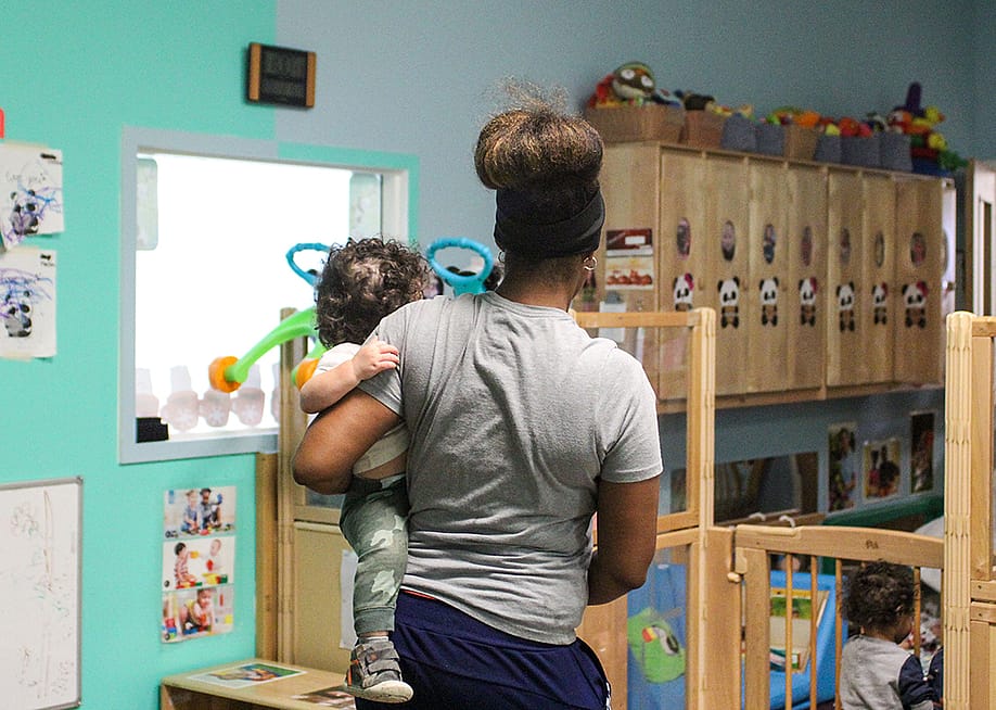 A child care teacher carrying an infant in a child care room. — Jackie Mader forThe Hechinger Report