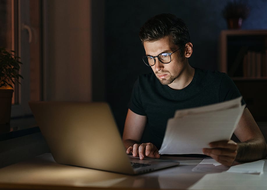 Tired young man working at home late at night. — Arsenii Palivoda // Shutterstock