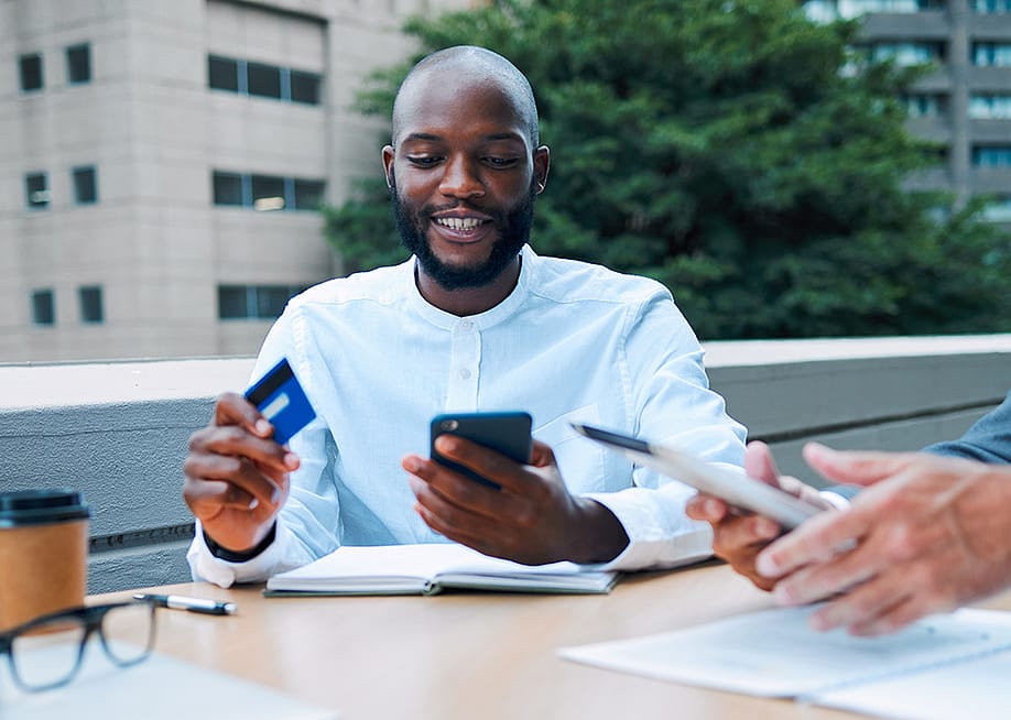 A young black businessman using a credit card to pay for a coffee shop transaction. — PeopleImages.com - Yuri A // Shutterstock