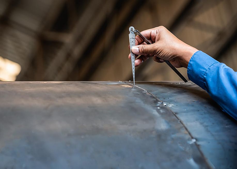 NDT inspector using welding gauge to inspect joint preparation or groove weld on a structure. — N_Sakarin // Shutterstock
