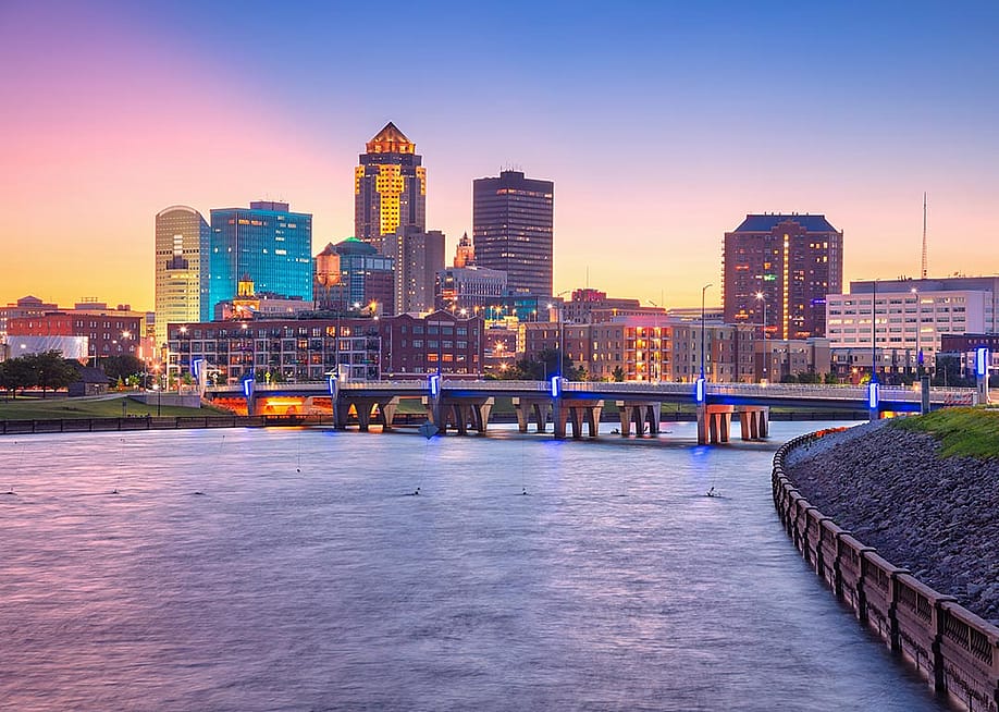 Cityscape image of Des Moines skyline, Iowa bridge over water with summer sunset. — Rudy Balasko // Shutterstock