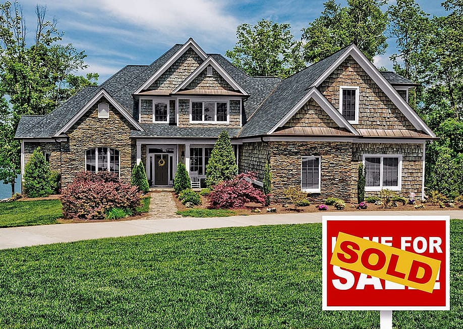 Home with green lawn and "For sale" sign covered by the word "sold." — Jeff Thrower // Shutterstock