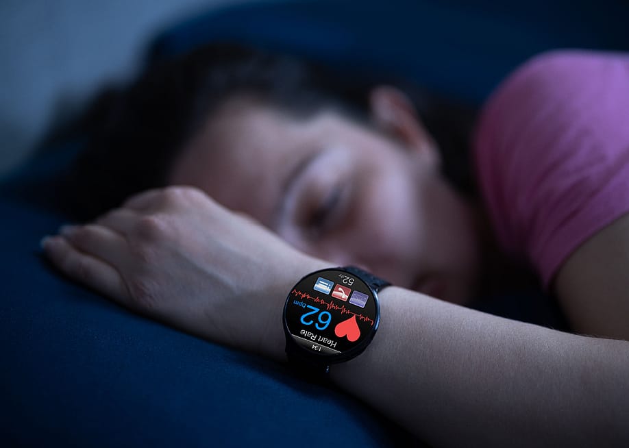 Person wearing sleep tracking heart rate monitor smartwatch in bed. — Andrey_Popov // Shutterstock