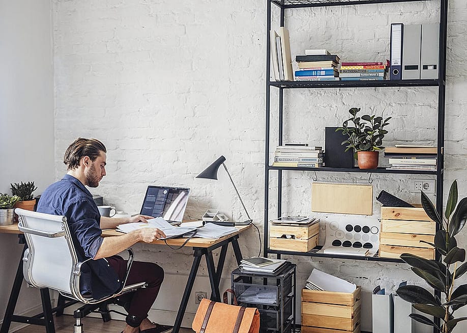 View of back of person sitting at a desk in white office chair in modern office with white walls. — LStockStudio // Shutterstock