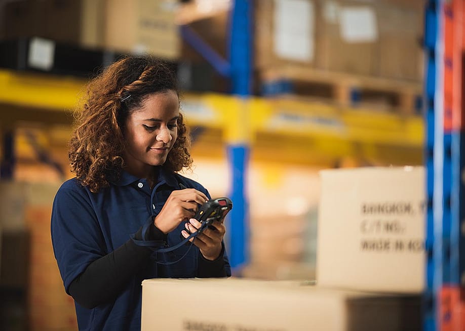 Warehouse worker using bar code scanner on boxed goods inside warehouse. — Chokniti-Studio // Shutterstock