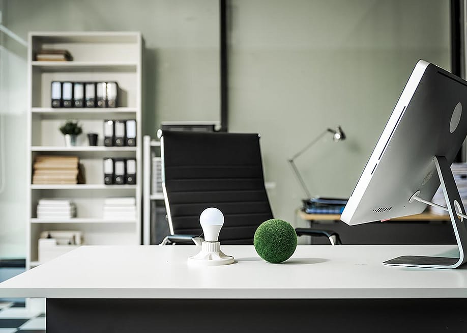 A modern empty office with a vacant chair behind a desk with a computer monitor and desktop decor. — PanuShot // Shutterstock