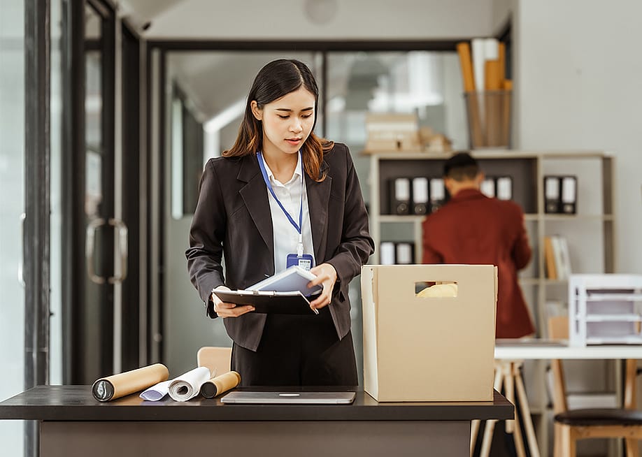 Young businesswoman preparing her work items to put in a box after being laid off. — M Isolation photo // Shutterstock