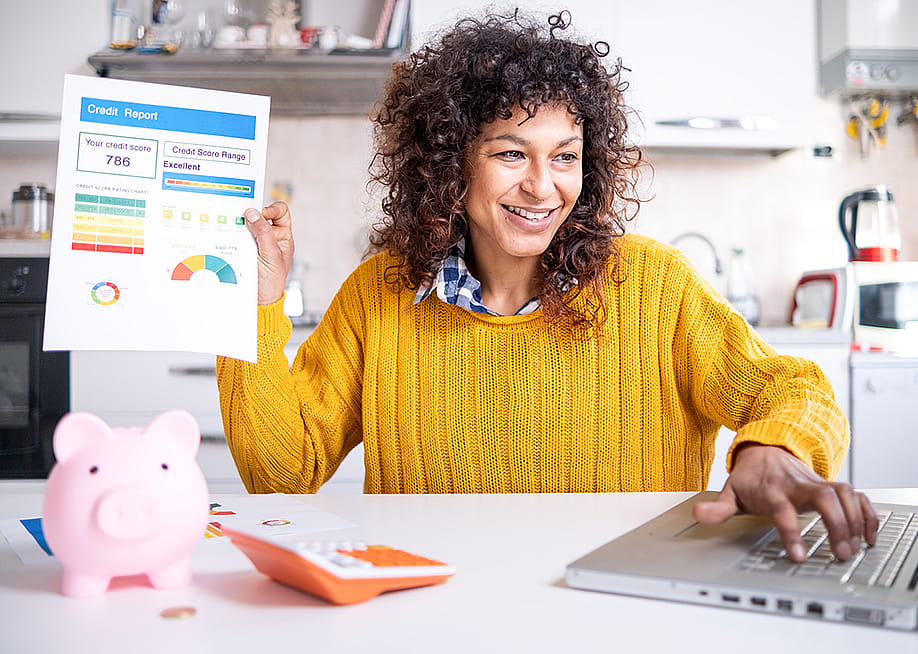 A woman happily holding up a good credit score report. — F01 PHOTO // Shutterstock