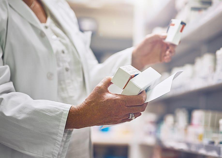 Pharmacist looking at multiple boxes of drugs. — PeopleImages.com - Yuri A // Shutterstock