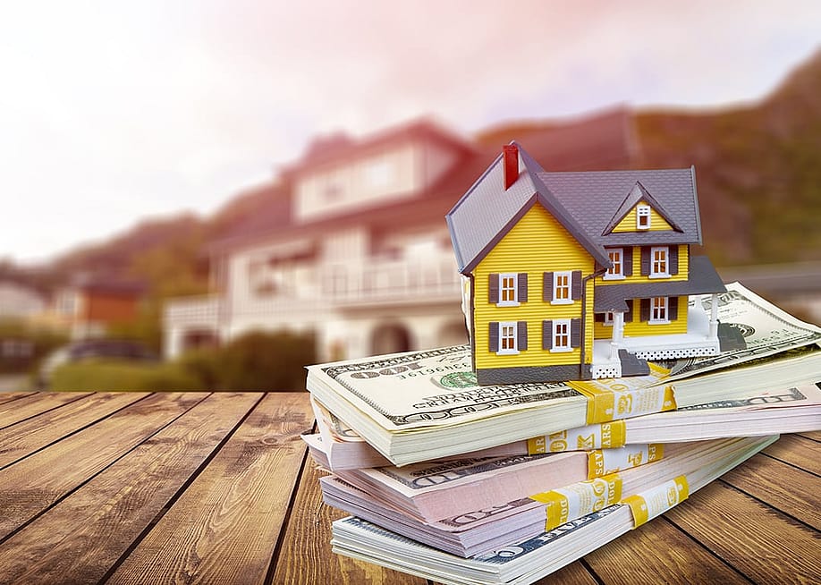 A figure of a house on top of bundles of cash. — Billion Photos // Shutterstock