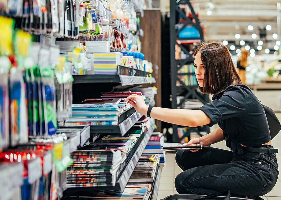 A young woman choosing school supplies at a supermarket. — siamionau pavel // Shutterstock