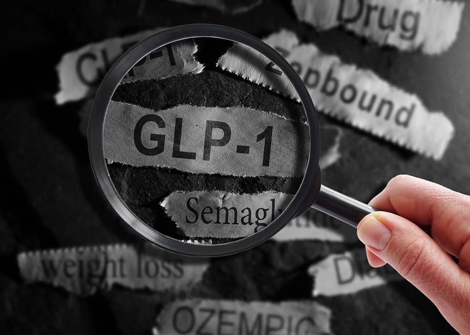 A magnifying glass over a ripped out piece of newspaper headline writing "GLP-1". — zimmytws // Shutterstock