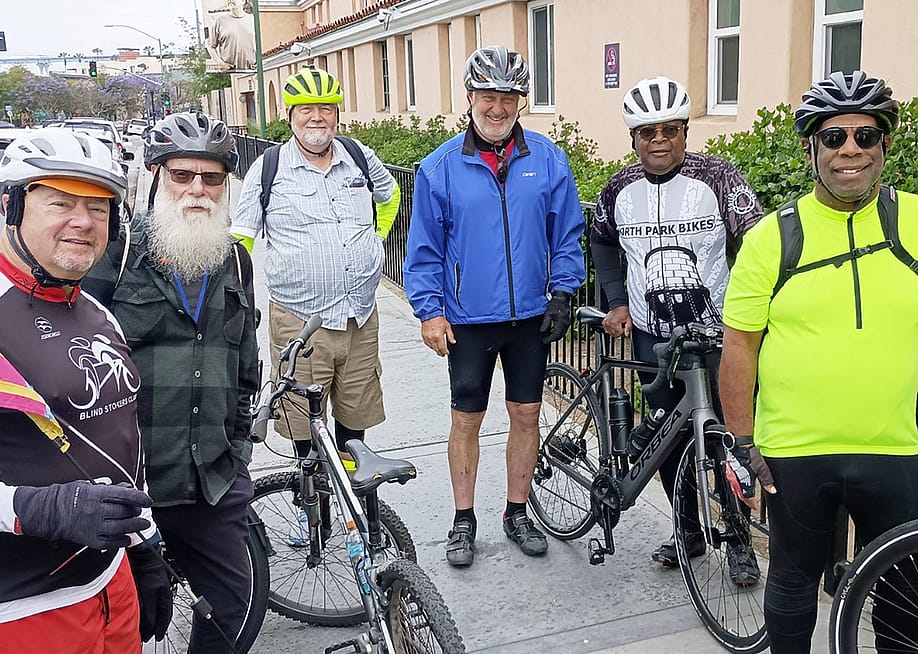 A group of participants in full biking gear posing for a photograph with their bicycles. — Courtesy of Father Joe’s Villages