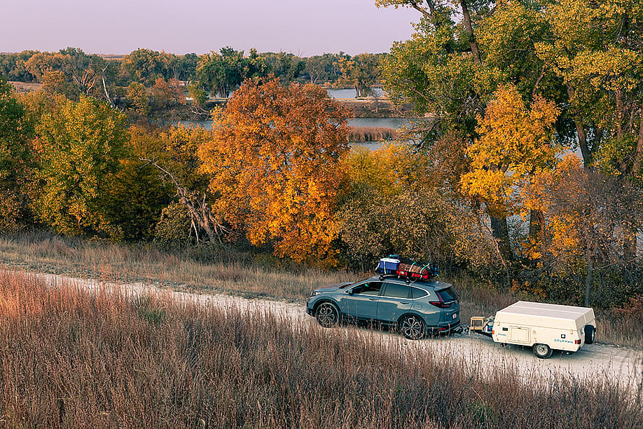 A blue 2020 Honda CR-V towing a 1990 Coleman Columbia pop-up camper on the road towards Antelope Lake in Kansas during autumn. — Tony Prato // Shutterstock
