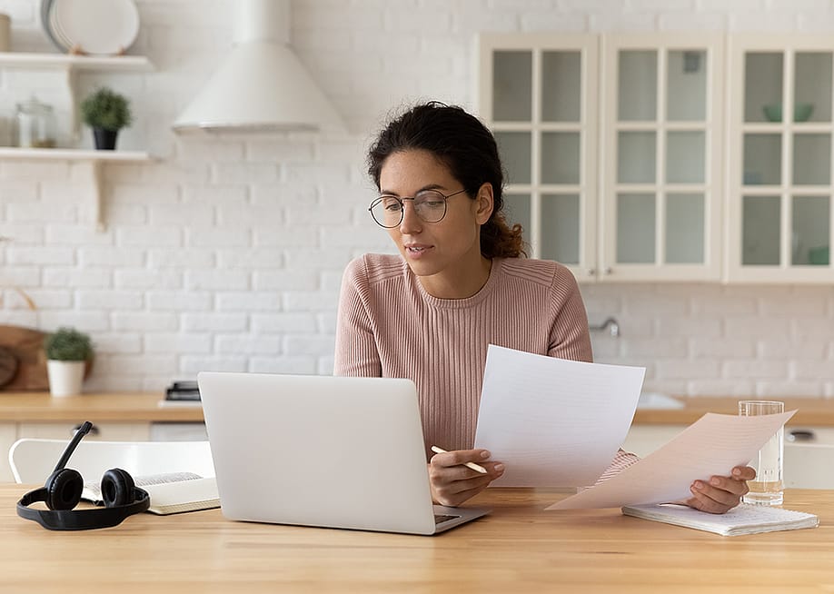 Young female at home using a laptop and reading financial documents. — fizkes // Shutterstock