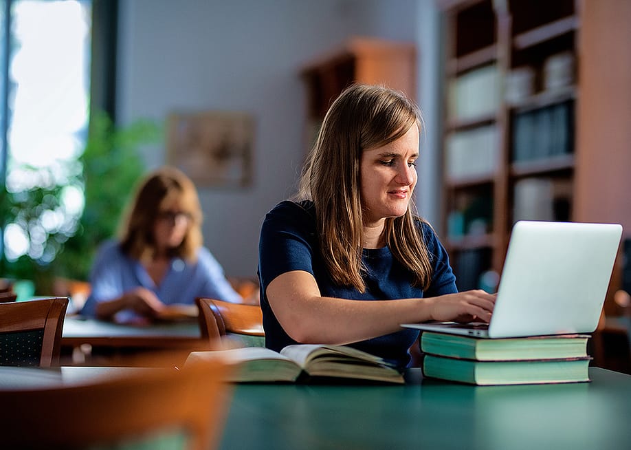 A visually impaired young woman studying in a university library. — Kinga // Shutterstock