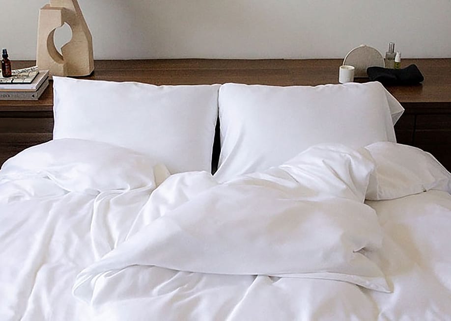 A double size bed with white sheets. — Lunya