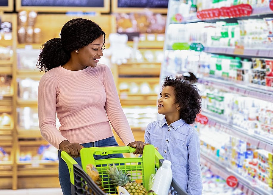 A young black mom and her daughter shopping together for groceries in a supermarket. — Prostock-studio // Shutterstock