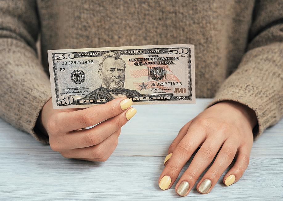 A woman holding a $50 banknote. — progressman // Shutterstock