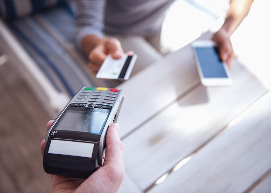 Person paying with a credit card at a cafe. — George Rudy // Shutterstock