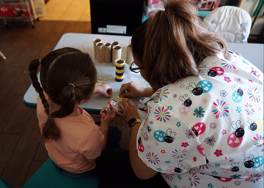 Maggi, a child care provider in New Mexico, with a preschooler in her care working on an art project. — Jackie Mader // The Hechinger Report