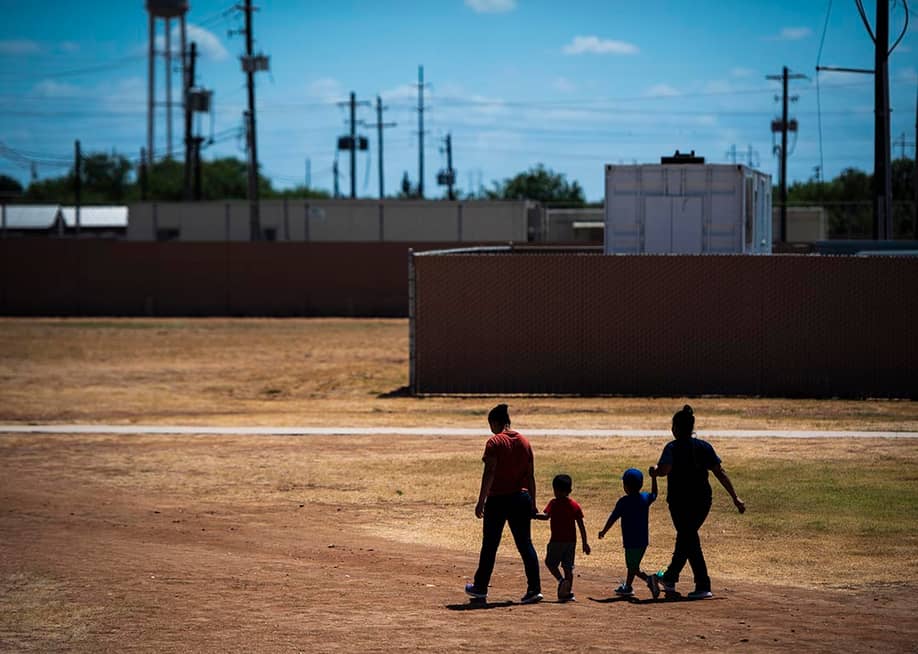 Immigrant woman and children walk across a field as U.S. Immigration and Customs Enforcement (ICE) and Enforcement and Removal Operations (ERO) hosts a media tour at the South Texas Family Residential Center, August 2019. — Jabin Botsford // The Washington Post via Getty Images