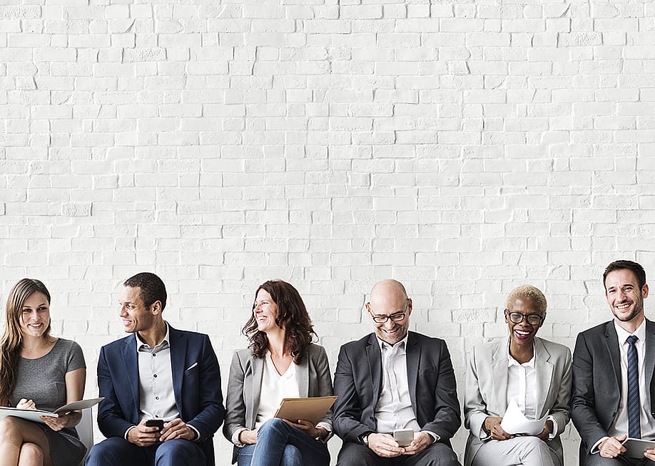 Professionals lined up sitting for a job interview. — Rawpixel.com // Shutterstock