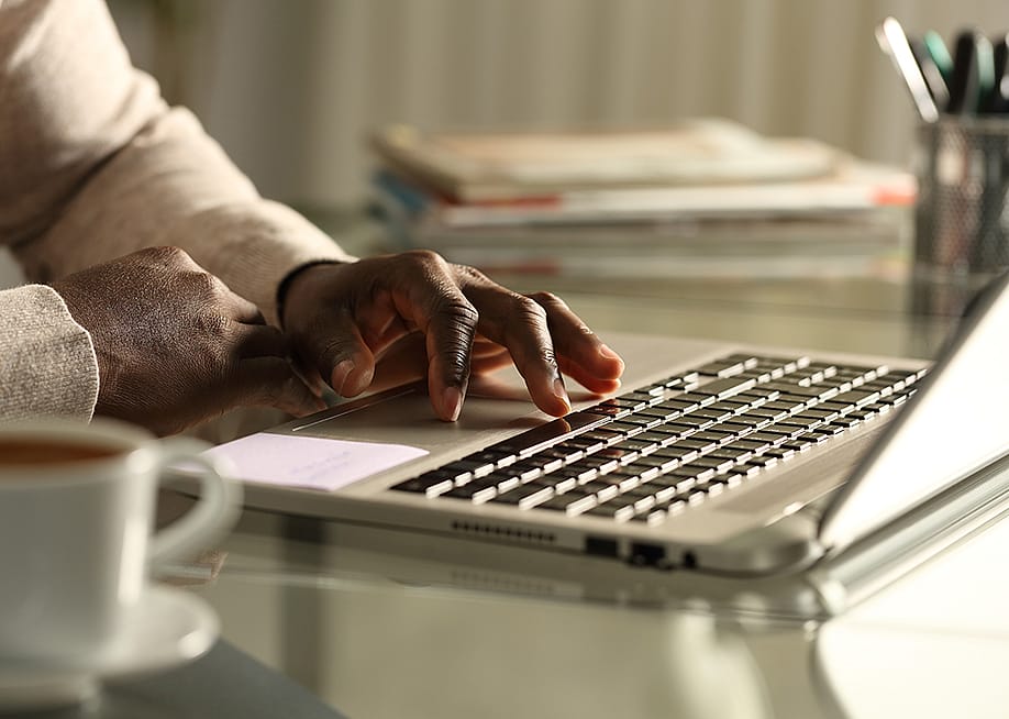 Close-up of a businessman using a laptop in the office at night. — Pheelings media // Shutterstock