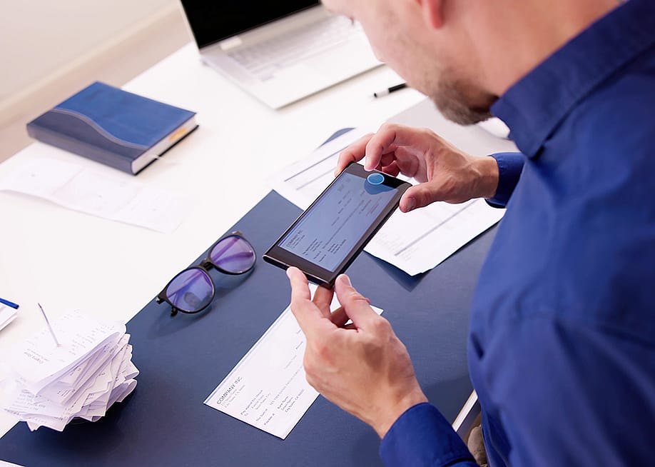 Business employee taking a photo of a deposit check. — Andrey_Popov // Shutterstock