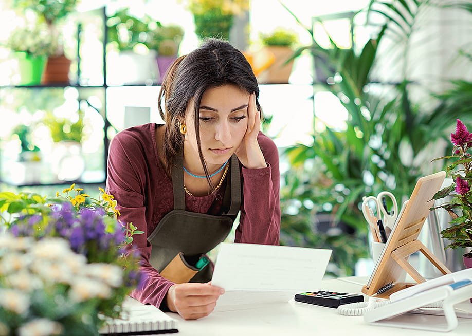 A small plants business owner worried looking at a bill. — Stock-Asso // Shutterstock
