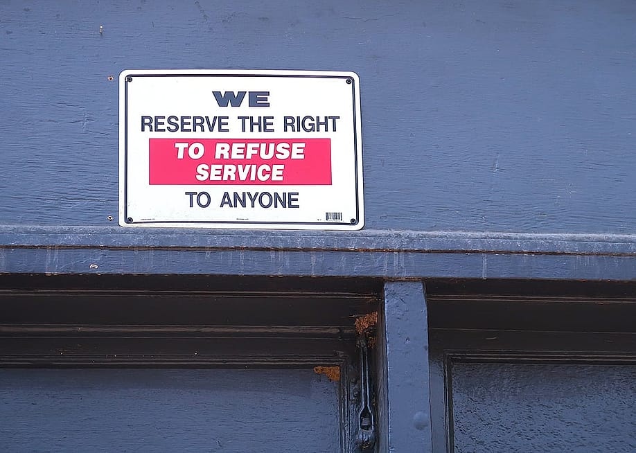 A "We reserve the right to refuse service to anyone" signage at a restaurant. — Red Herring // Shutterstock