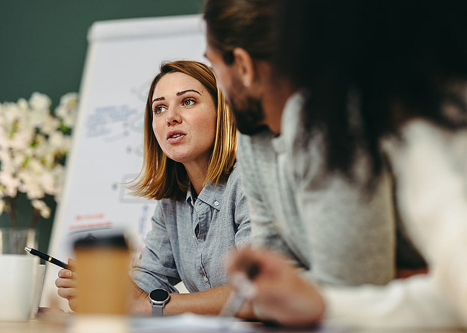 Businesswoman having a discussion with her colleagues in a meeting room. — Jacob Lund // Shutterstock