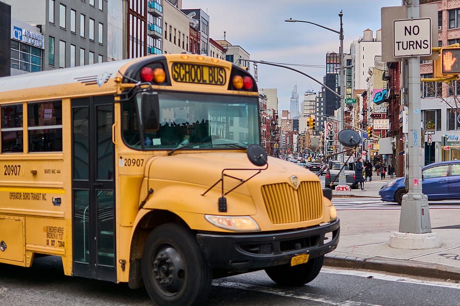 A yellow school bus passing a street in New York City. — Mundofoto // Shutterstock
