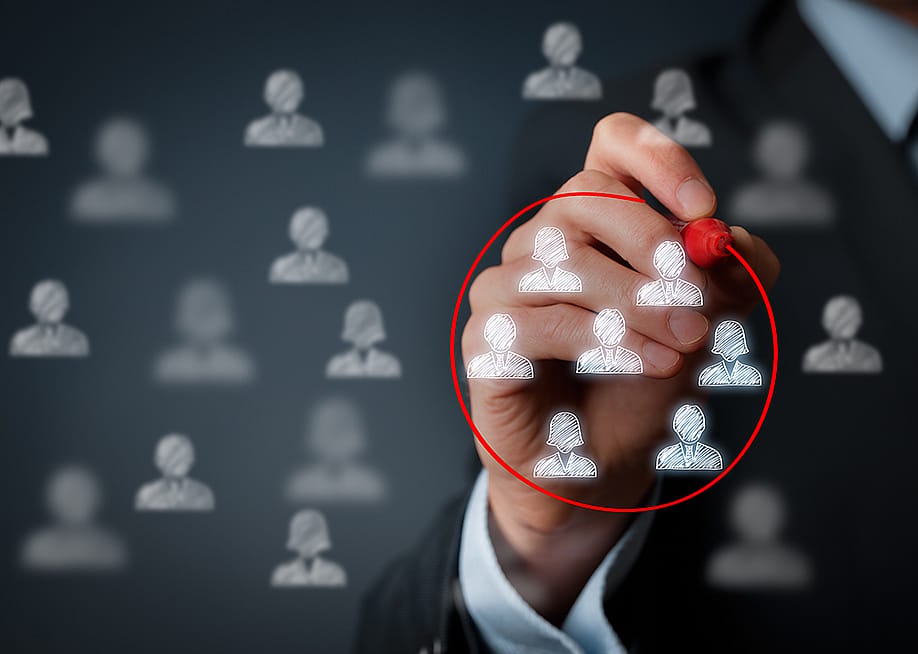 A hand encircling a group of business people graphic figures with a red marker. — Jirsak // Shutterstock