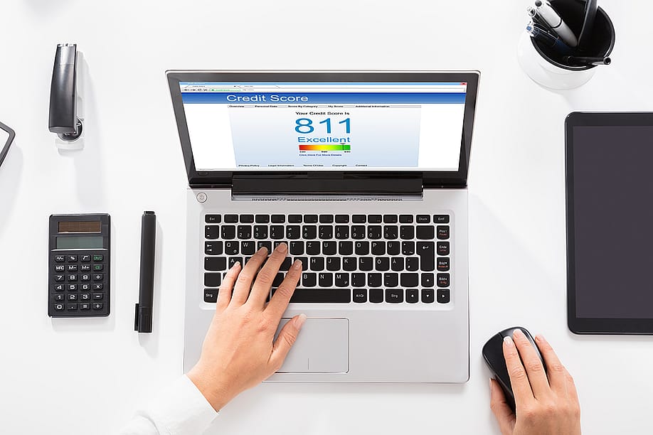 An office table with a laptop showing credit score. — Andrey_Popov // Shutterstock