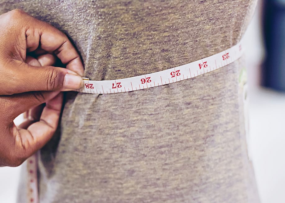 A tailor taking measurements of a client's torso with a tape measure. — SUPAWADEE3625 // Shutterstock