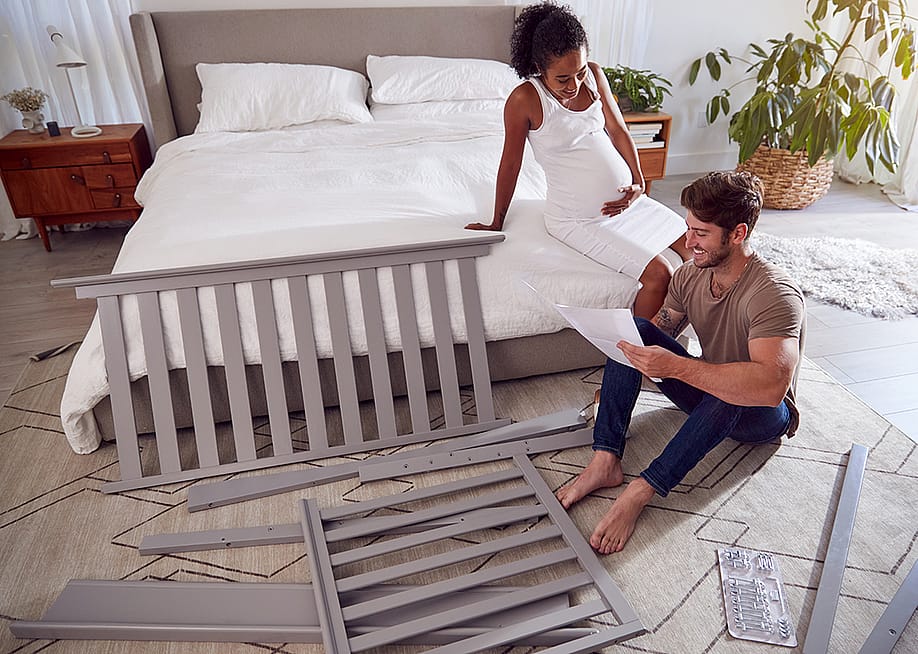 An expecting couple reading instructions on how to set up a cot. — Monkey Business Images // Shutterstock