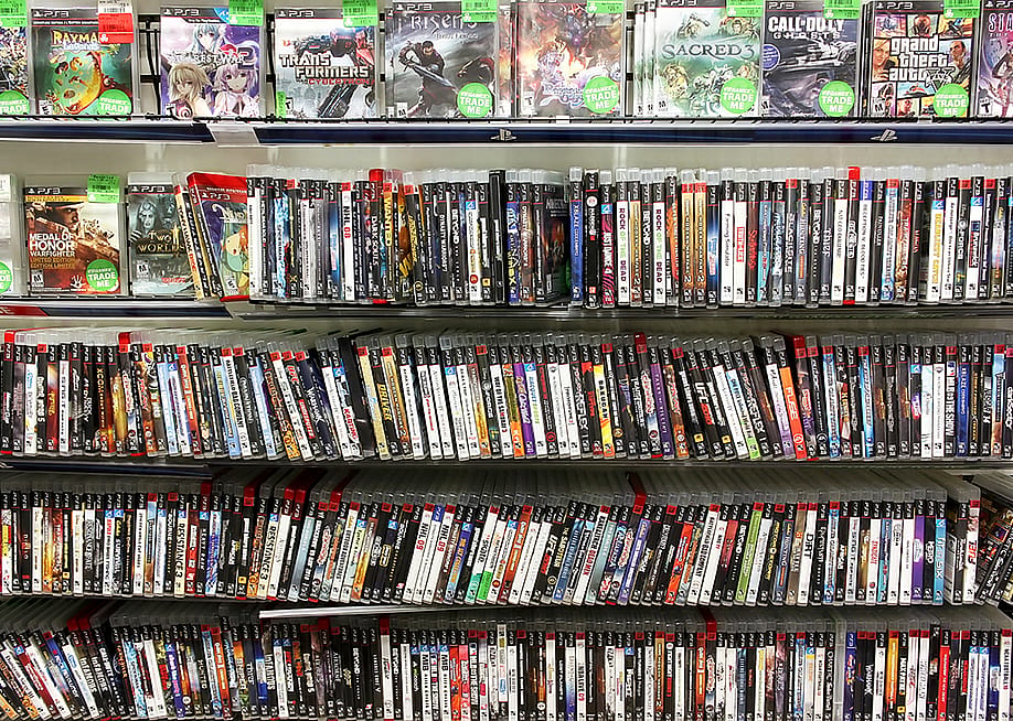 PlayStation game discs on display at a game store. — Niloo // Shutterstock