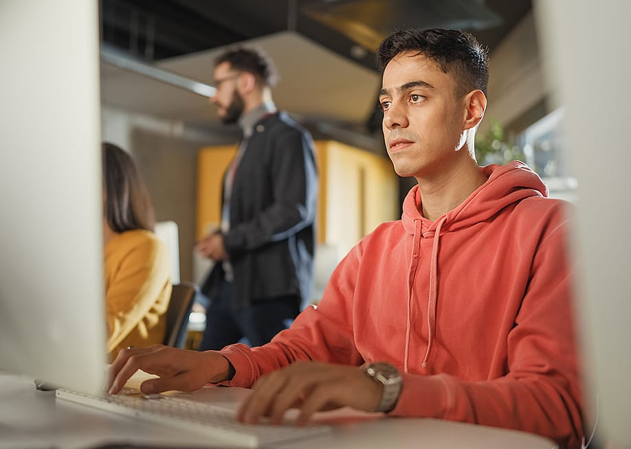 A male student using a desktop computer for application tasks. — Gorodenkoff // Shutterstock